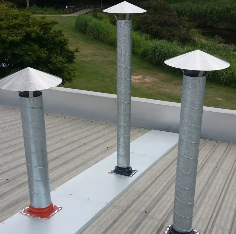 Three flue pipes with rain caps on a metal roof