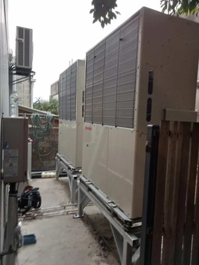 Two large commercial outdoor gas units on raised steel stands beside a building