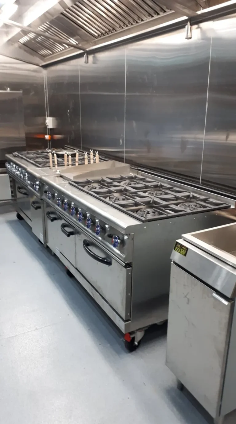 Commercial kitchen gas cooking range under a stainless steel canopy