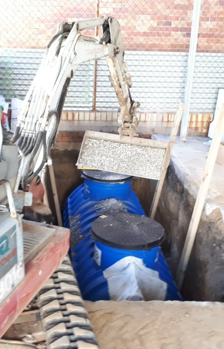 Blue underground tank being installed in an excavated pit
