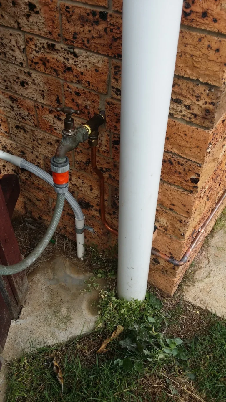 Garden tap and water pipe against a brick wall