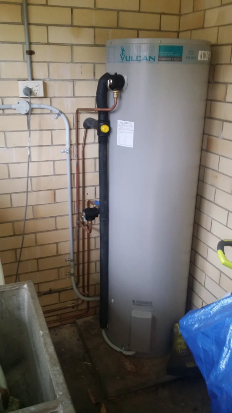 Hot water storage tank installed beside a brick wall