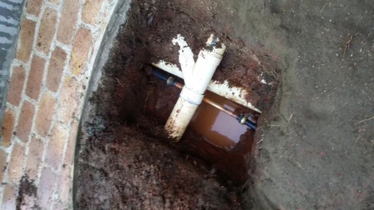 Exposed sewer pipe junction in an excavated hole