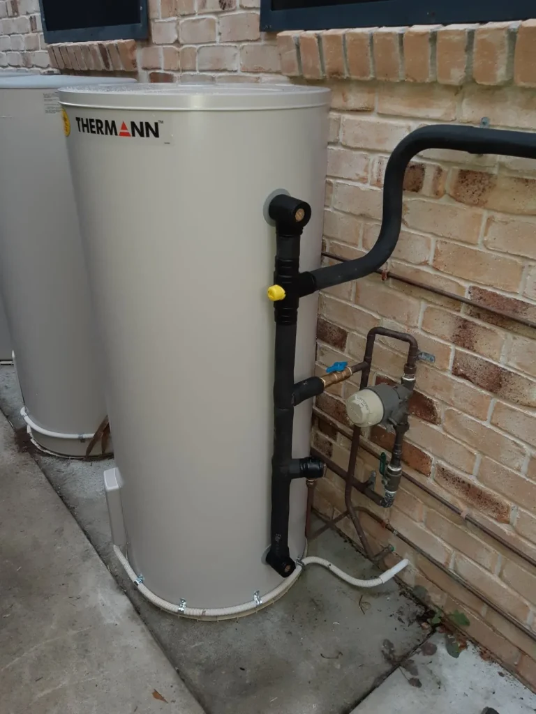 Thermann electric hot water tank beside a brick wall