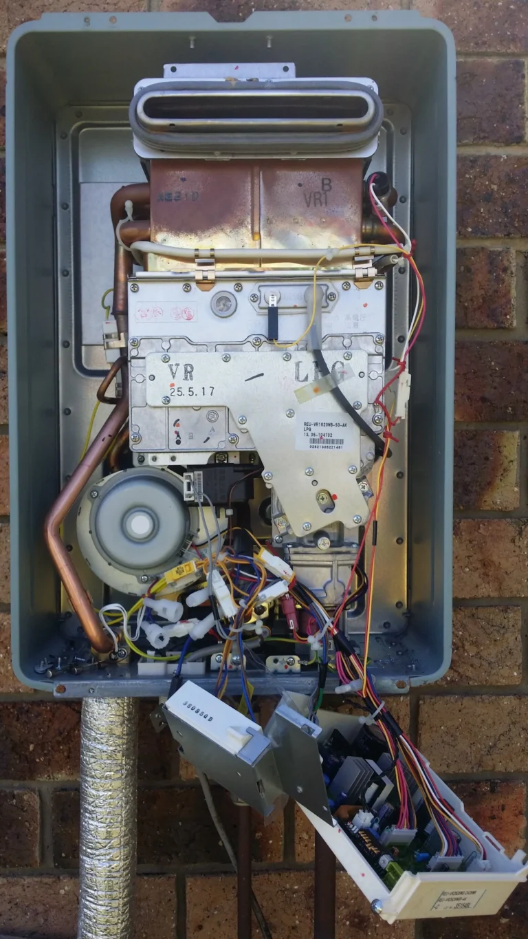 Gas hot water unit opened up for repair, showing the burner, controls and wiring