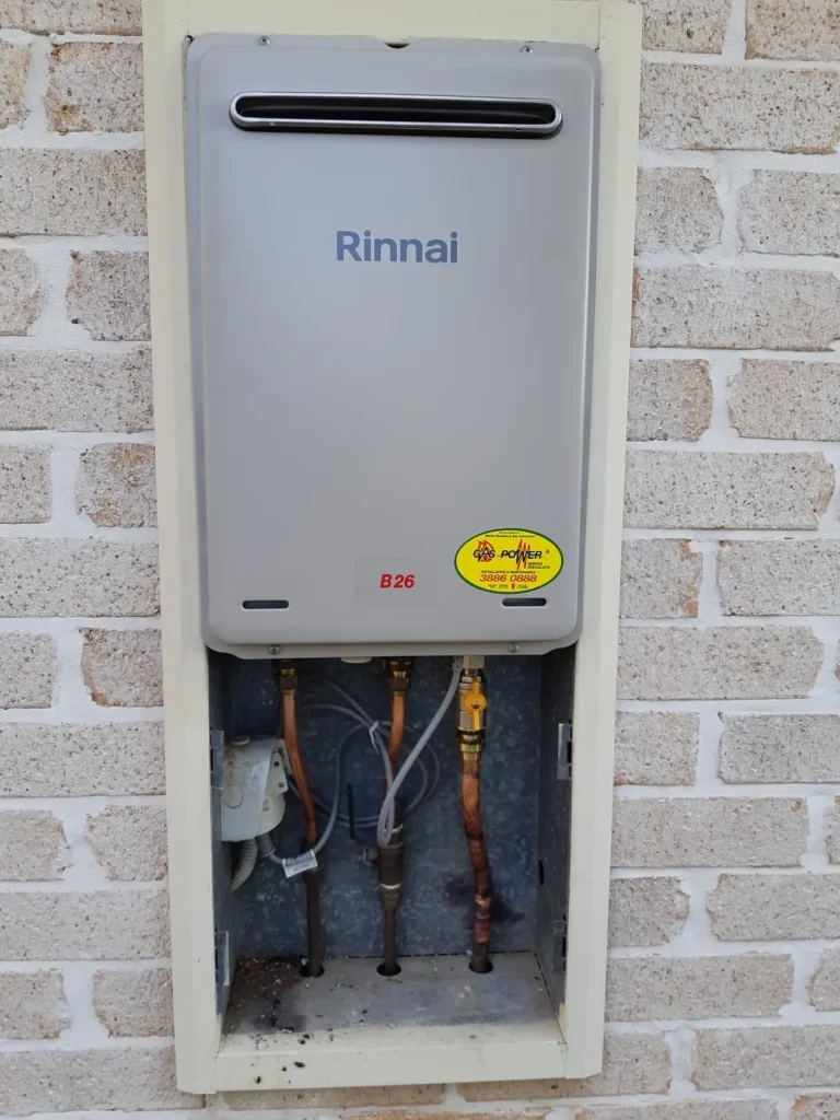 Rinnai gas hot water unit on a brick wall with its connections exposed for repair